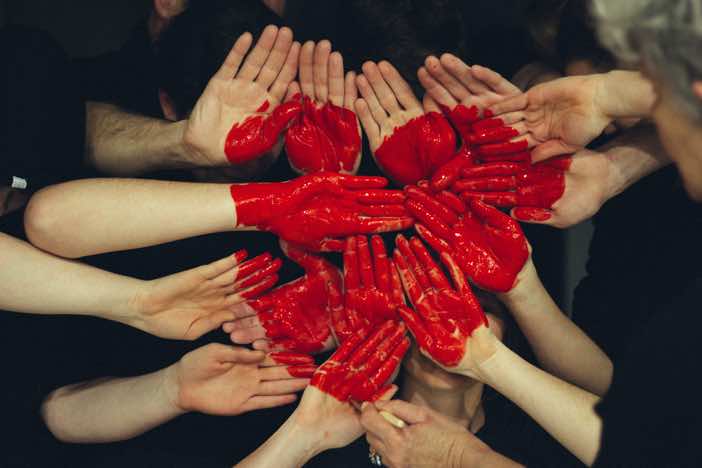 Hands painted red in a heart shape
